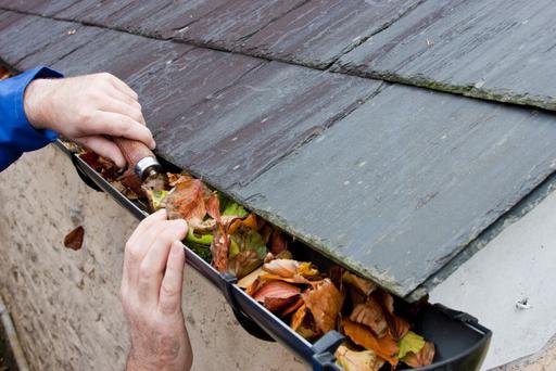 Man cleaning gutter of obstructions to prevent water-ingress