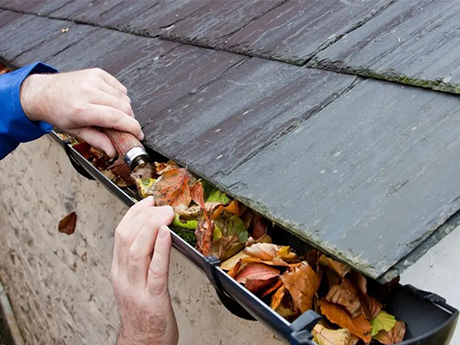 Man cleaning gutter of obstructions to prevent water-ingress